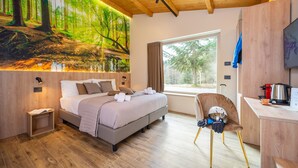A modern bedroom with a large forest mural, a bed with pillows, a chair, and a desk with a kettle. - Villa dei Larici (Spezzano della Sila)