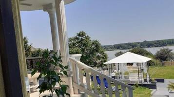 A covered outdoor area with a white railing, a gazebo, and a view of a lake.