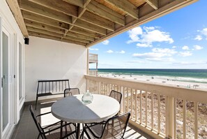 A balcony with a table and chairs, overlooking a beach with a wooden ceiling and a view of the ocean. - Gulf-Front Retreat w/ Stunning Views, Private Beach Access, & Community Pool (Panama City Beach)