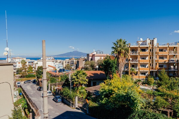 Un quartier résidentiel offrant une vue sur une montagne au loin, une rue bordée de voitures garées et un immeuble à plusieurs étages doté de balcons.