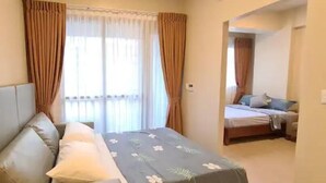 A bedroom with a bed, a sofa, and a window with curtains.