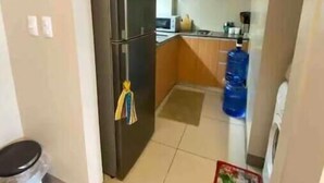 A compact kitchen with a refrigerator, microwave, and a water dispenser.