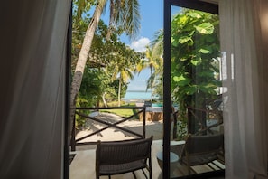 A balcony with wicker chairs, a view of a beach, and palm trees. - Azulea Bacalar Hotel & Spa - Lagoon Front (Bacalar)