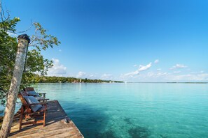 A wooden dock with two chairs and a table, overlooking clear turquoise water with a distant island and sailboats. - Azulea Bacalar Hotel & Spa - Lagoon Front (Bacalar)