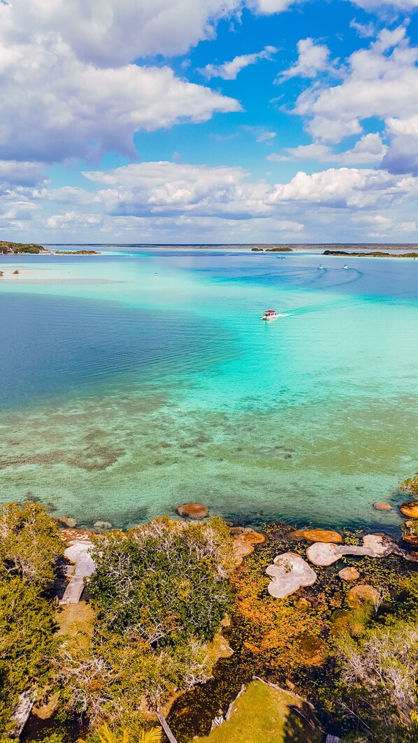 A coastal landscape with clear turquoise waters, rocky outcrops, and dense vegetation. - Azulea Bacalar Hotel & Spa - Lagoon Front (Bacalar)