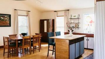 A modern kitchen with wooden cabinetry, a central island, and a dining area with wooden chairs.