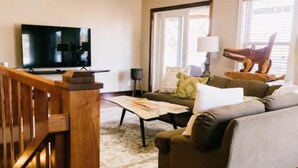 Ein Wohnzimmer mit einer Couch, einem Couchtisch, einem Fernseher und einer Treppe.