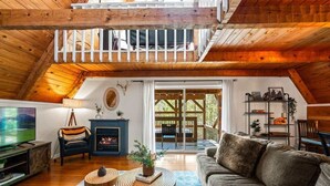 A cozy loft-style living room with a fireplace, wooden floors, and a balcony.