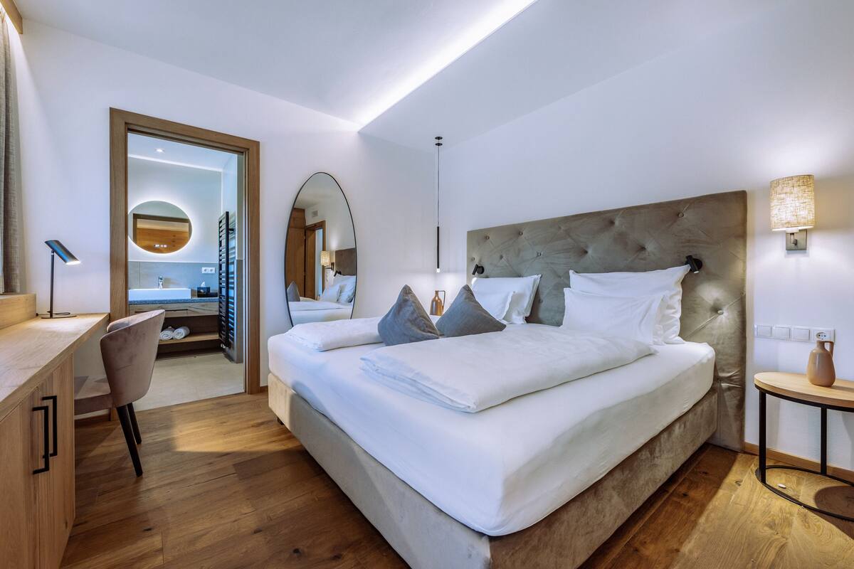 Une chambre d’hôtel moderne avec un grand lit, un bureau et un miroir.