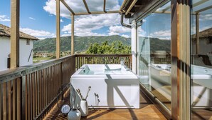 A balcony with a wooden railing, a white table, and a view of mountains. - Ansitz Rungghof (Appiano Sulla Strada del Vino)