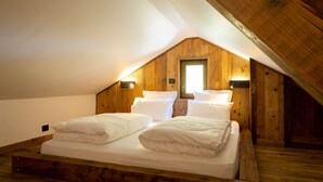 Una camera da letto con soffitto a falde, pareti in legno e due letti con biancheria bianca.
