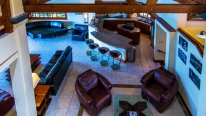 Un espacio habitable amplio con un sofá curvo, una mesa de centro y una zona de bar con taburetes.