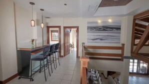 Una cocina amplia con barra, una escalera y un cuadro grande en la pared.