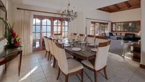 Comedor con una gran mesa dispuesta para seis personas, rodeada de sillas, y vistas al exterior a través de amplios ventanales.