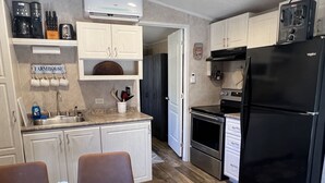A compact kitchen with white cabinets, a black refrigerator, and a wooden dining table. - Escape to Bryson City, just a quick ride away from Great Smoky Mountains (Bryson City)