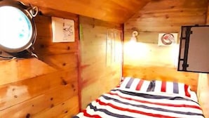 A small, wooden room with a bed featuring a striped bedspread. - Exceptionnel. Bateau Logement (Ailly-sur-Somme)