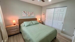 Un dormitorio con cama, mesitas de noche, ventilador de techo y armario.