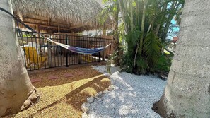 A hammock tied between two concrete pillars, a thatched-roof structure, and a palm tree. - Turtle Nest 1 - Quick Walk to Beach (Fort Myers Beach)