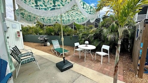 Un patio al aire libre con una parrilla, asientos y una mesa techada.
