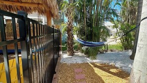 A fenced outdoor area with a hammock, palm trees, and a gravel path.