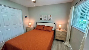 Un dormitorio con cama, mesitas de noche y una obra de arte en la pared.