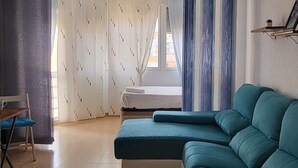 A living room with a sectional sofa, a ceiling fan, a window with curtains, and a tiled floor. - TERRASOL PLAZAMAR 4-2 (Torre del Mar)
