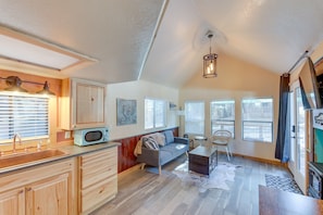 A compact living space with a kitchenette, a sofa, a dining table, and a ceiling fan.