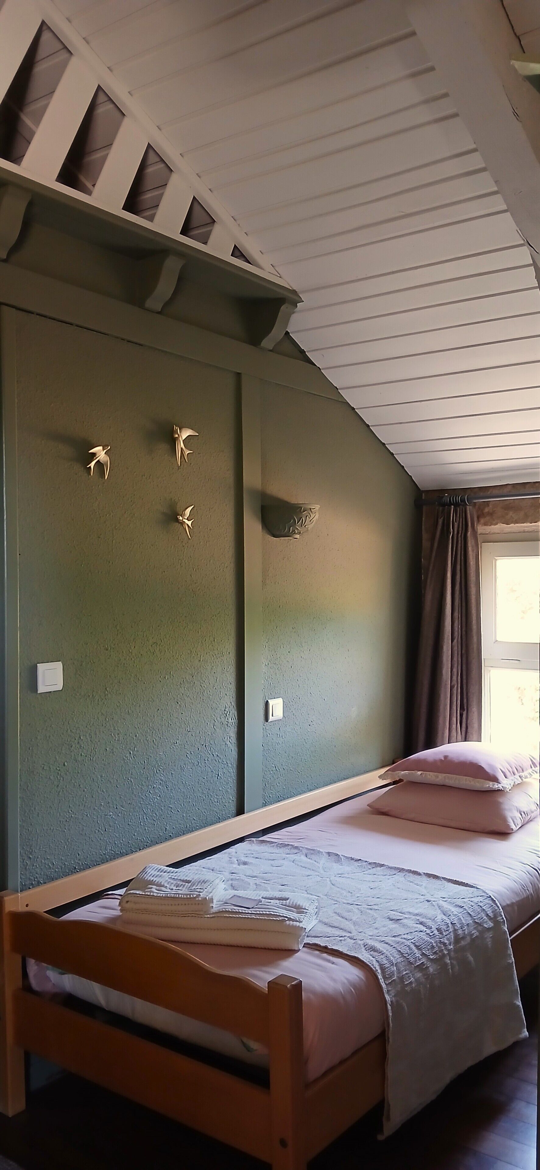 A room with a bunk bed, a window with curtains, and a wall with three bird-shaped decorations.