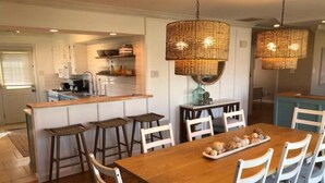 Une cuisine moderne dotée d’un îlot central, de tabourets de bar et de luminaires suspendus.