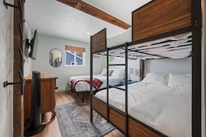A compact room with a bunk bed, a desk with a chair, a mirror, and a window with a view. - Little White Cottage Lake Michigan sandy beach (Sturgeon Bay)