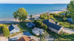 A residential area with houses, a beach, and a view of the ocean. - Little White Cottage Lake Michigan sandy beach (Sturgeon Bay)