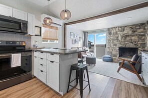 Una cocina moderna con una isla central, una chimenea de piedra y un comedor con vistas.