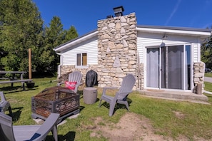 Una casa de fachada de piedra, un porche cubierto con mobiliario exterior y un ventanal corredera.