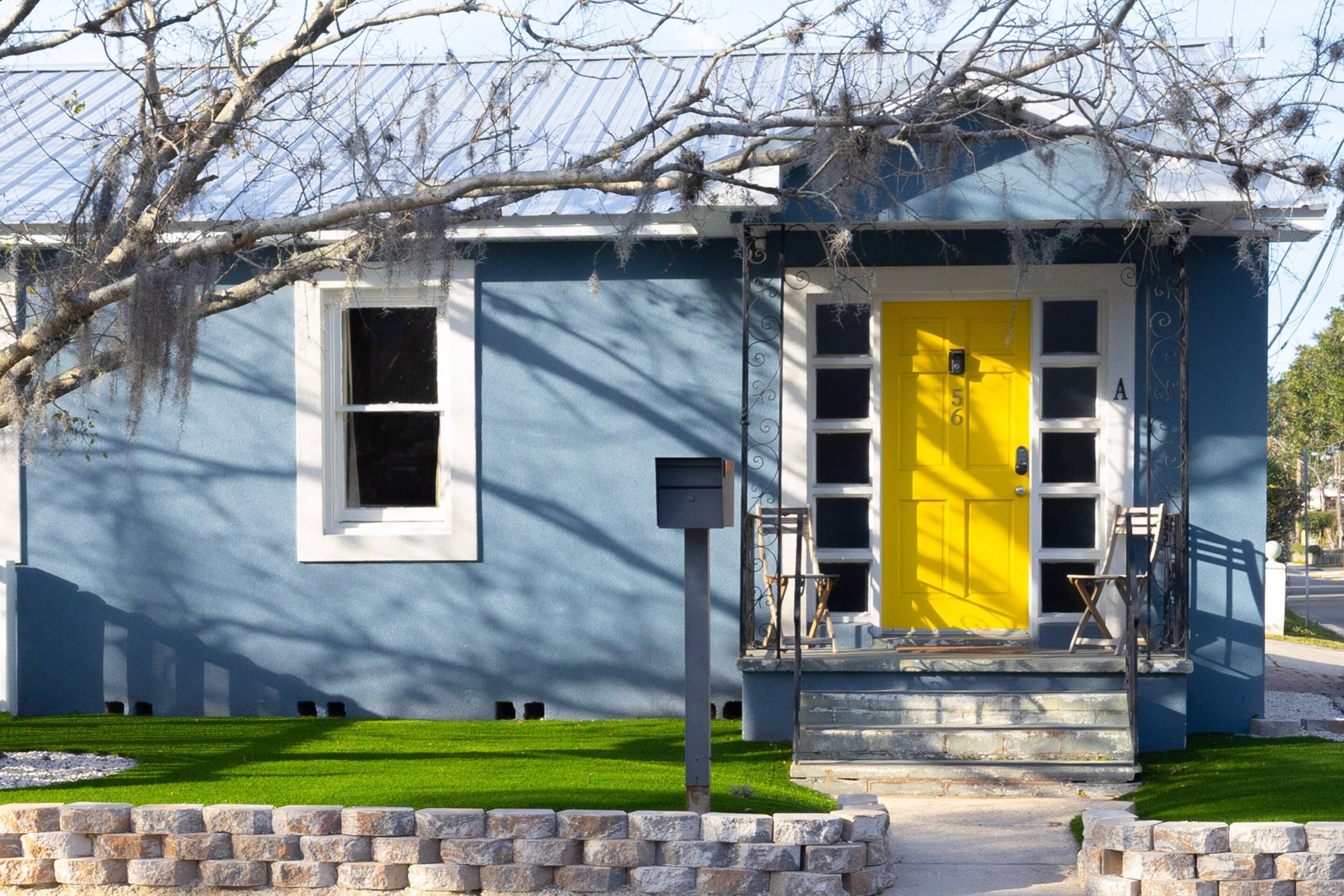 Una casa a due piani con una porta giallo brillante e un piccolo portico.