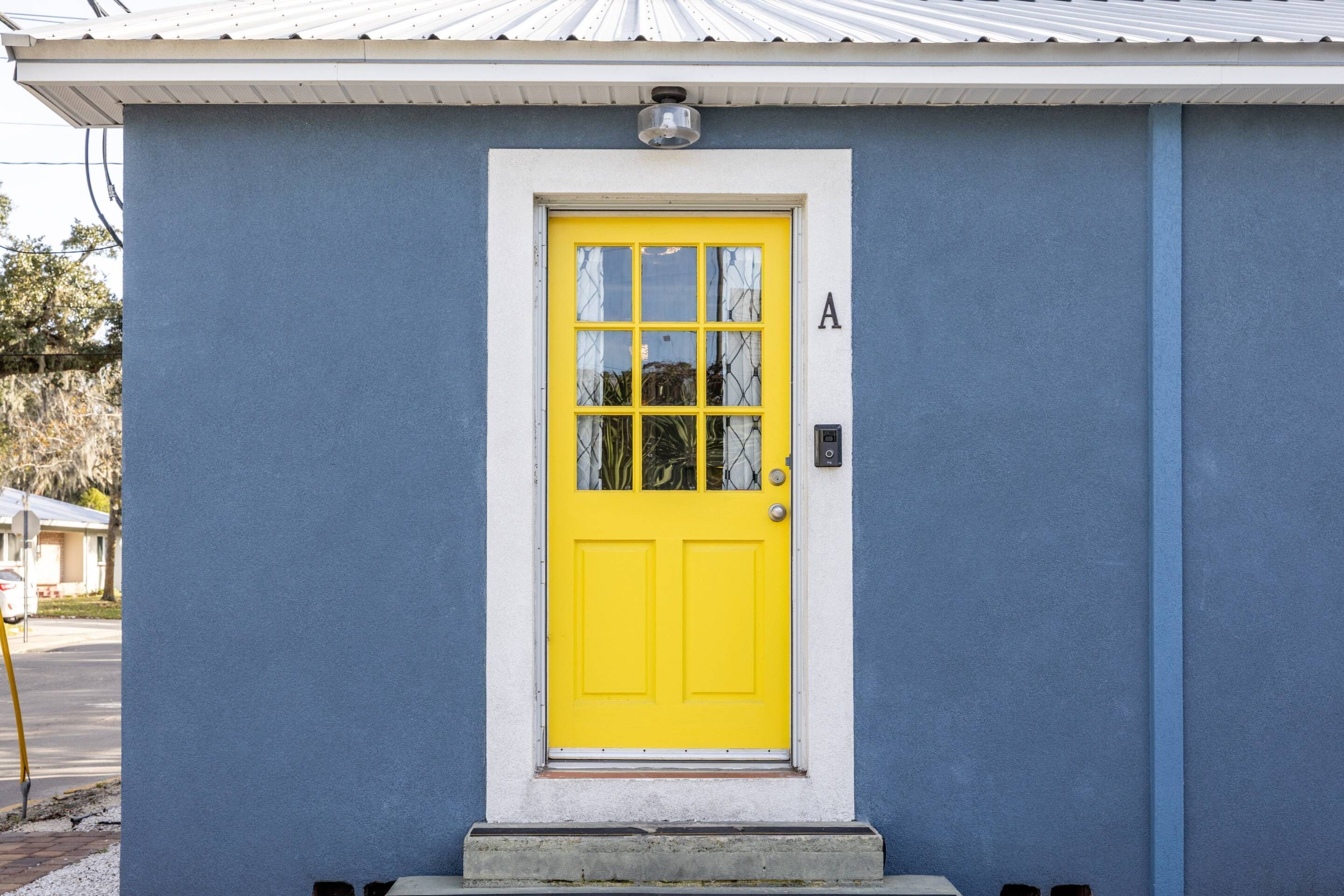 A blue building with a bright yellow door, a small porch, and a mailbox.
