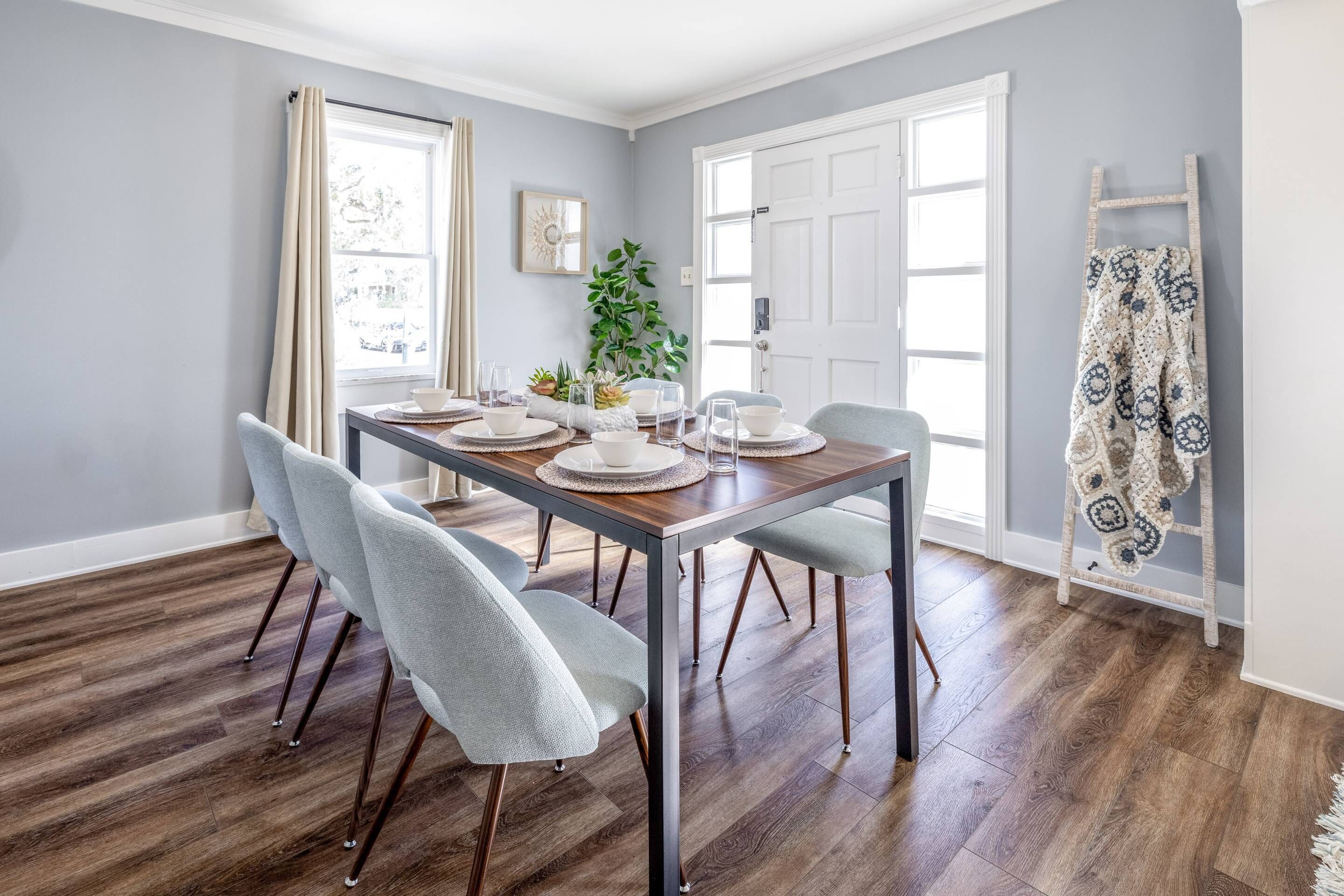 Un coin repas avec une table en bois, des chaises grises et une porte blanche.