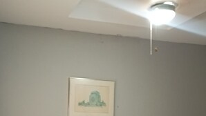 Een hotelkamer met een bed, nachtkastje, lamp en een plafondlamp.