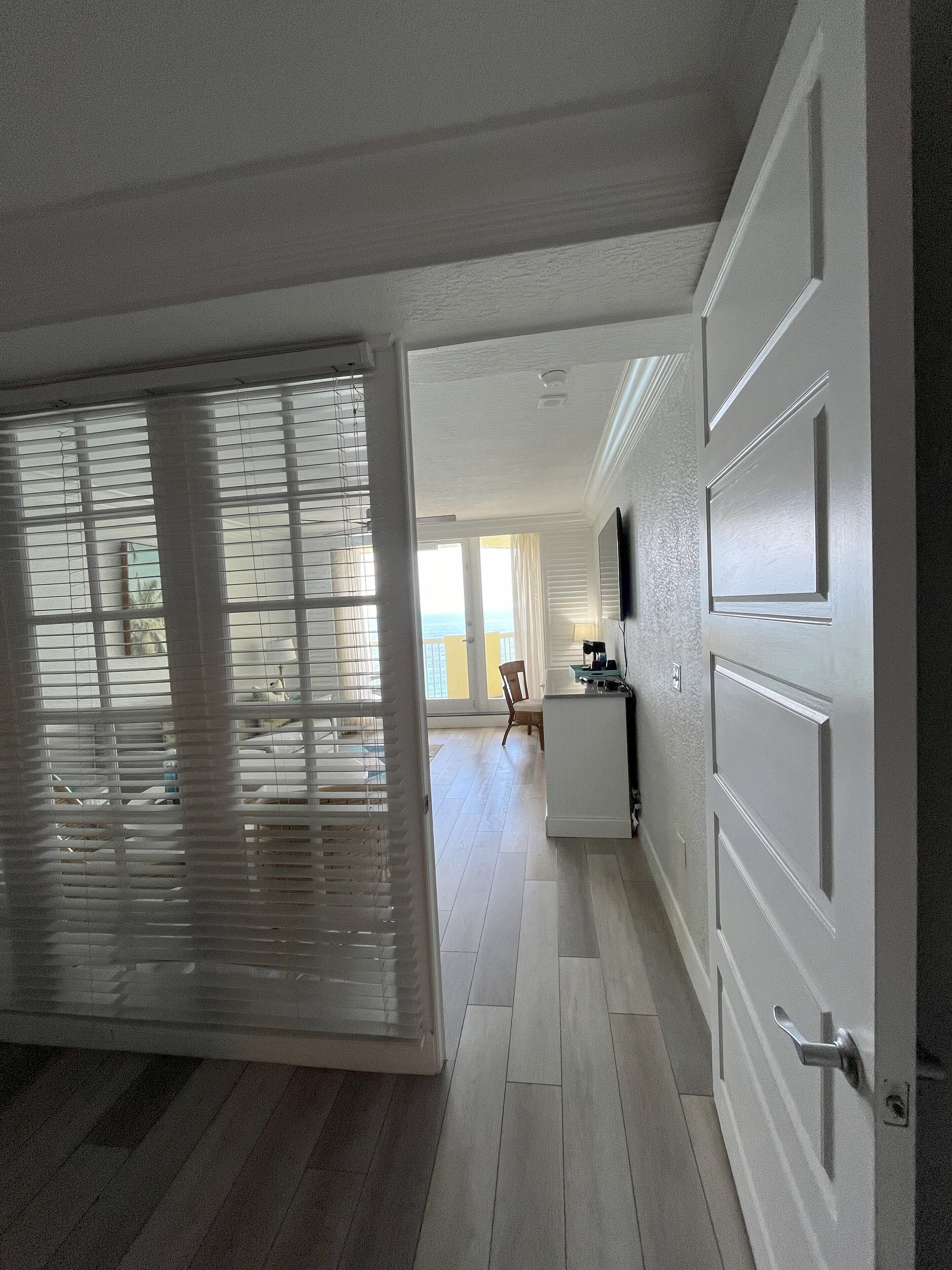 Una habitación con un ventanal grande, una puerta y una zona de cocina con mostrador y electrodomésticos.
