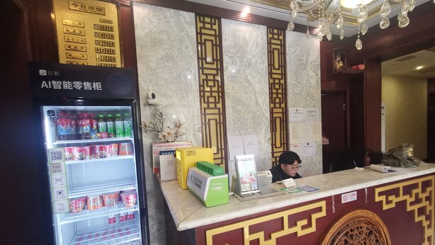A hotel reception area with a marble counter, a vending machine, and a decorative wall panel. - Beijing Huiqing Garden Bussiness Hotel (Beijing)