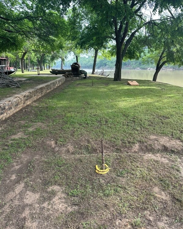 A grassy area with a brick wall, a wooden bench, and a small tree.