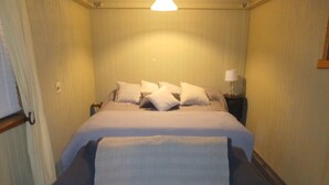 Une chambre à coucher avec un lit, des oreillers, une table de chevet avec une lampe et un banc.