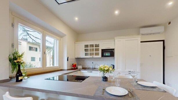 A modern kitchen with a central island, white cabinetry, and a large window. - Charming terrace apartment (Firenze)