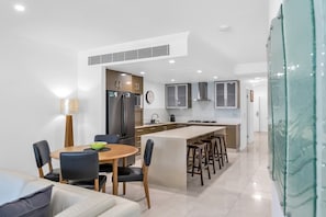 Une cuisine moderne dotée d’un îlot central, d’un coin repas avec des chaises et d’une horloge bien visible.