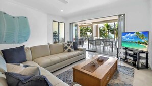 A modern living room with a sofa, coffee table, TV, and a view of the outdoors.