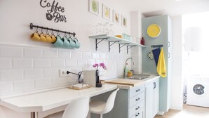 A modern kitchen with white countertops, a coffee bar sign, and a hanging rack with mugs. - Beachfront apartment with terrace  (Sanlúcar de Barrameda)