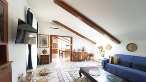 A spacious living room with a high ceiling, a blue sofa, a wooden coffee table, and a tiled floor. - Casa Raffaela by Wonderful Italy (Napoli)