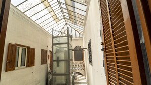 A narrow corridor with a glass ceiling, wooden shutters, and a staircase leading to an upper level. - Casa Raffaela by Wonderful Italy (Napoli)