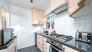 Una cocina moderna con baldosas blancas tipo metro, una estufa a gas, un tostador y un horno empotrado.