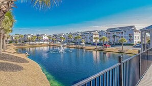 A waterfront property with a pool, palm trees, and modern buildings in the background. - Charming 2BR Condo w/Pools, Hot Tub & Waterway Views Near Myrtle Bch Attractions (Myrtle Beach)