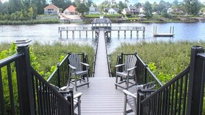 A wooden deck with chairs leading to a dock over a lake, surrounded by houses. - Charming 2BR Condo w/Pools, Hot Tub & Waterway Views Near Myrtle Bch Attractions (Myrtle Beach)